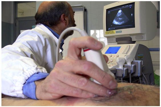 Medico che esegue un'ecocardiografia con la sonda sul torace del paziente, osservando il monitor