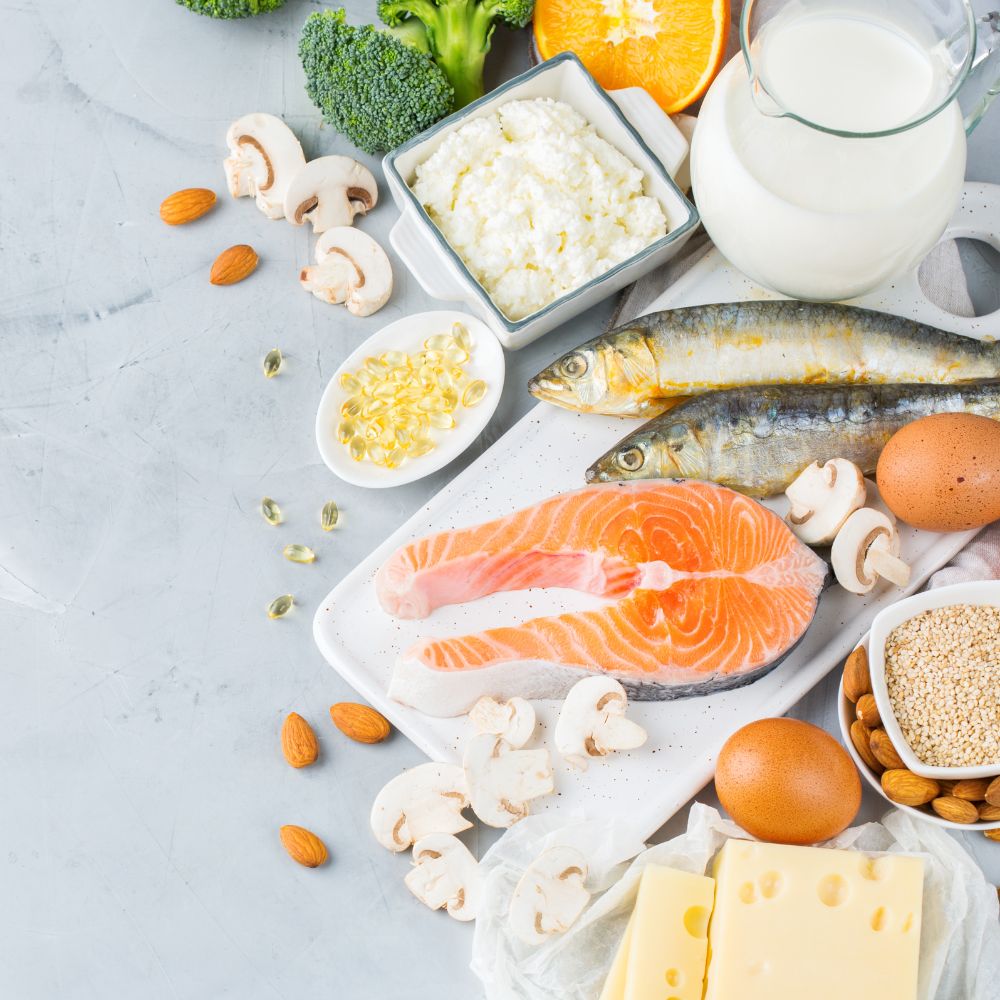 Salmone, sardine, uova, latte, ricotta, formaggi, funghi, mandorle e capsule di integratore su un tavolo