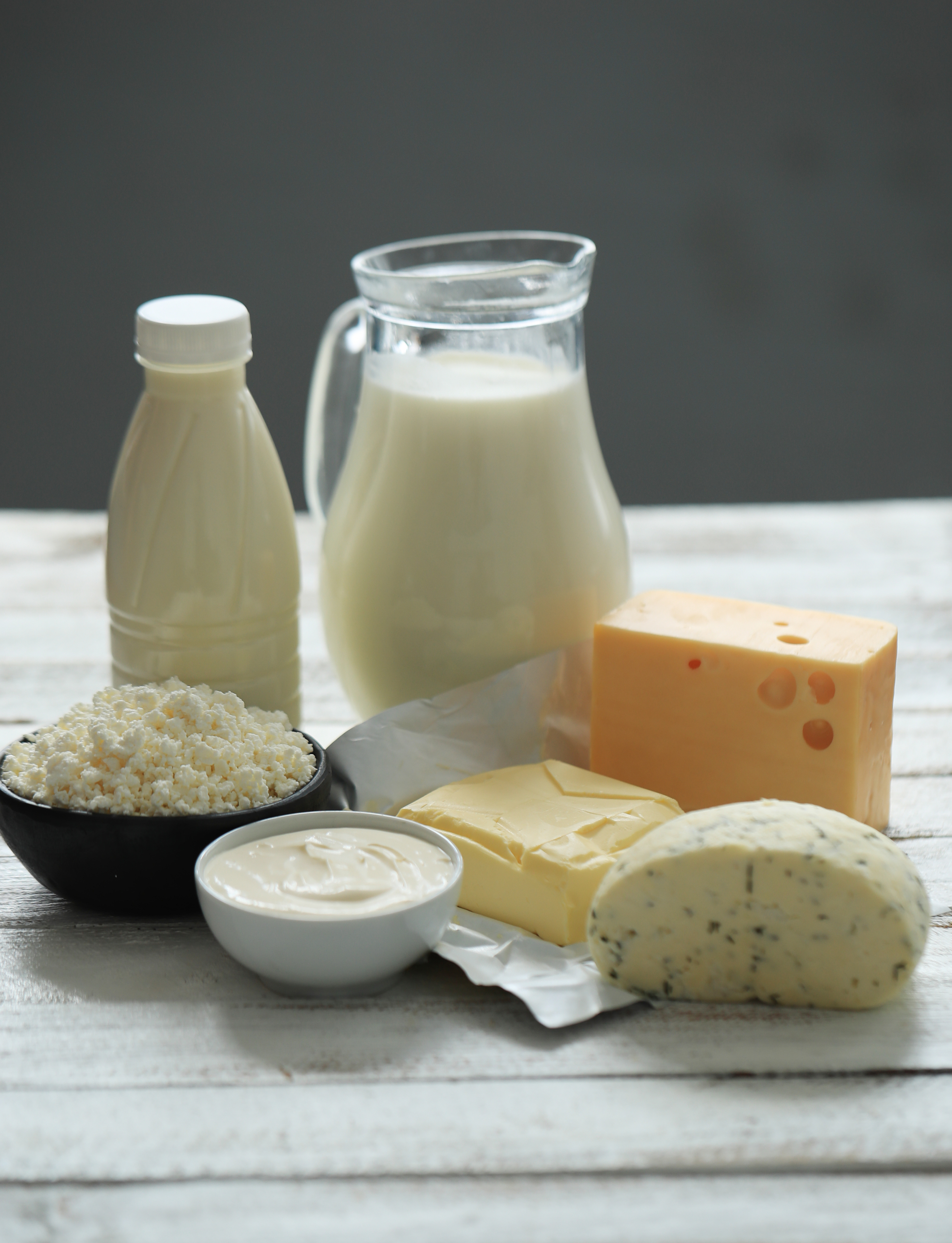 Latticini su un tavolo di legno: latte, fiocchi di latte, yogurt, burro e formaggi