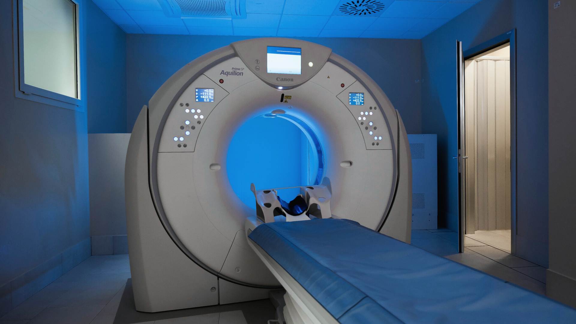 Sala TAC con il tomografo computerizzato e il lettino, illuminata da luce blu