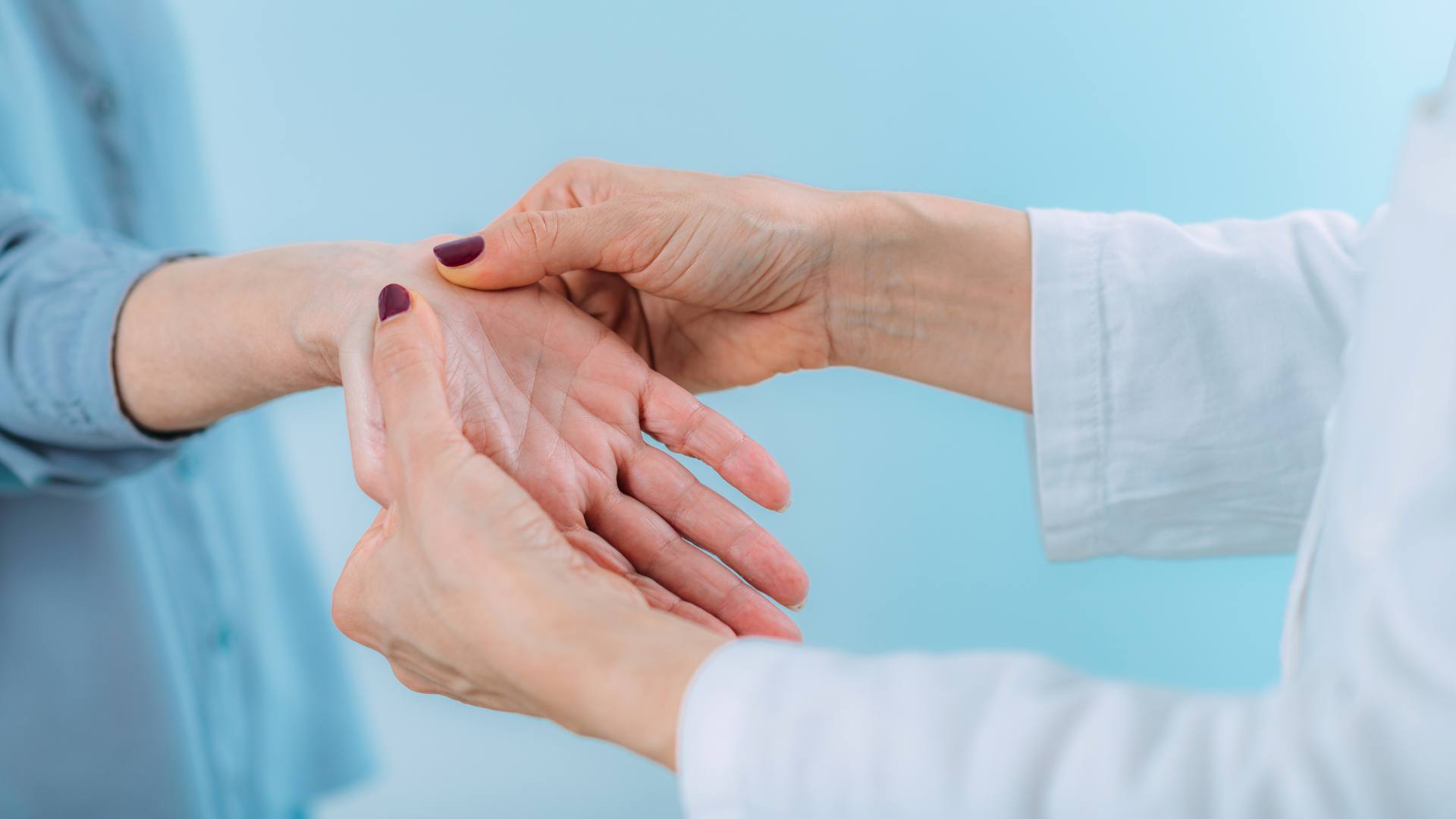 Specialista in camice bianco che esamina la mano di una paziente