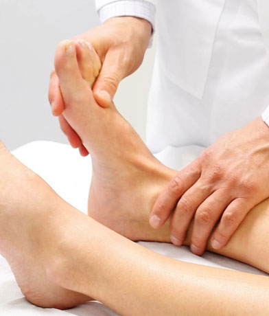 Medico che tiene il piede di una paziente sul lettino e ne controlla la flessione
