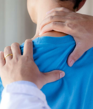 Medico appoggia le mani sulla spalla e sul collo di un paziente con maglietta azzurra